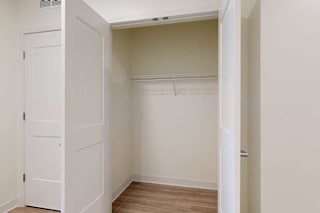 A white closet with a door and a shelf.