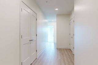 A long hallway with white doors and wood floors.