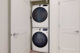 A white washing machine is in a small space between two doors.