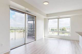 A spacious lviing room with a view of the outdoors through large windows.