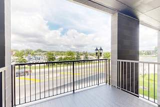 A balcony with a view of a parking lot and trees.
