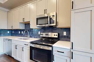 A kitchen with white cabinets and stainless steel appliances