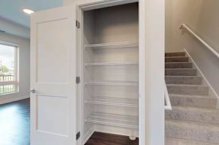 Empty shelves in a closet next to a staircase.