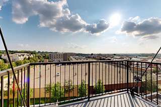 A balcony overlooks a cityscape with buildings and greenery.