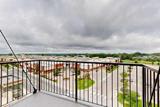 A balcony overlooks a parking lot and buildings.