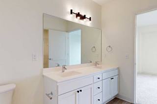 A white bathroom with a sink, mirror, and toilet.