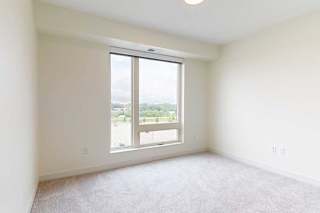 A large, empty bedroom with a window overlooking a parking lot.