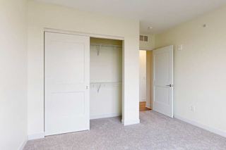 A white closet door is open in a bedroom with carpeted floor.