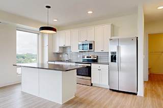 A modern kitchen with white cabinets and stainless steel appliances.