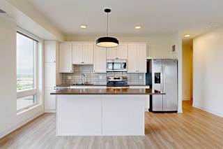 A modern kitchen with white cabinets and a wooden floor.