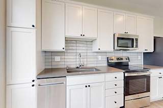 A kitchen with white cabinets and stainless steel appliances.