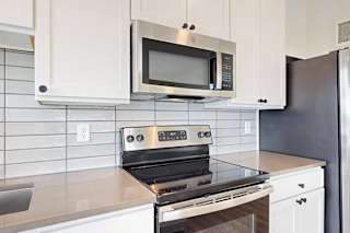 A modern kitchen with a stainless steel oven and microwave above it.