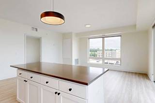 A kitchen with white cabinets and an island with brown countertop.