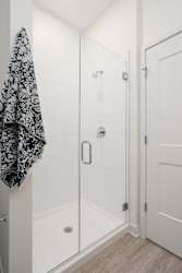 Walk in shower with glass door and towel hanging on rack to the right
