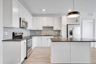 Large kitchen with countertop island white cabinets and matching stainless steel appliances at The Rowan Apartments in Eagan Minnesota