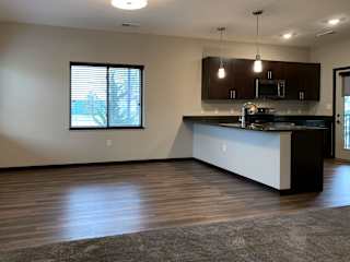 Dining next to kitchen with hard wood style flooring at the villas at mahoney park