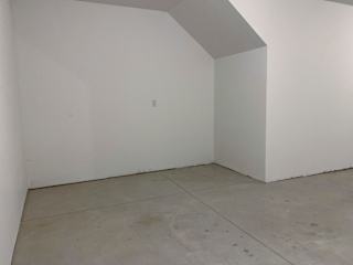 A white room with a concrete floor and a white wall.