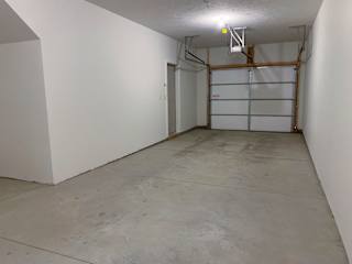 A large empty garage with a white door and a white ceiling light.