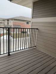 A balcony with a black railing and wooden floor.