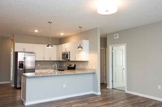 A kitchen with a refrigerator, microwave, and sink.