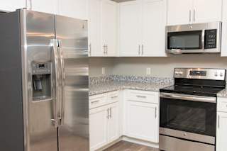 A kitchen with a stainless steel refrigerator, microwave, and oven.
