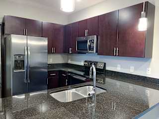 A kitchen with a granite counter top and stainless steel appliances.