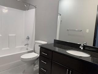 A bathroom with a white toilet and a black counter top.
