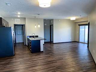 A kitchen with a refrigerator, sink, and cabinets.