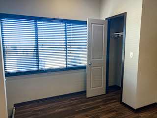A room with a door and a window with blinds.