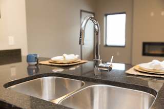 A modern kitchen with a stainless steel sink and faucet.