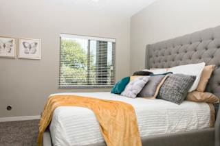A bedroom with a large bed and a window with blinds.