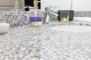 A bathroom counter with a soap dispenser and a sink.