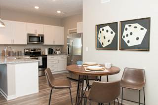 A kitchen with a table and chairs and two paintings on the wall.