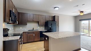 a kitchen with dark cabinets, black appliances, and light granite countertops