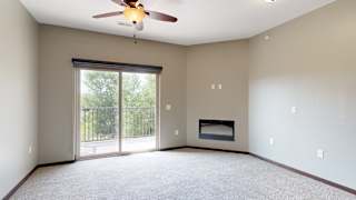 a carpeted living room with an electric fireplace, a ceiling fan, and sliding glass door to a balcony