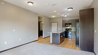a kitchen with dark cabinets, black appliances, light granite countertops and hardwood flooring