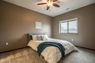 A bedroom with a bed, a ceiling fan, and a window.