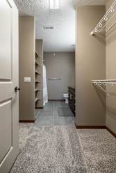 A walk-in closet with a carpeted floor and that leads into bathroom