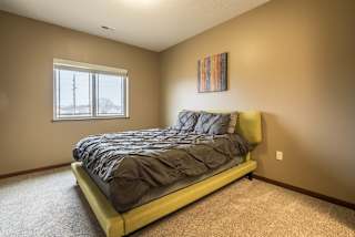 A bedroom with a bed, carpet, and a painting on the wall.