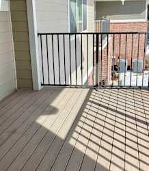 A balcony with a black metal railing and wooden floor.