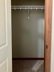 A hall closet with a built-in overhead shelf.