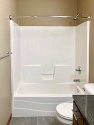 A bathroom with a white tub shower with chrome fixtures.