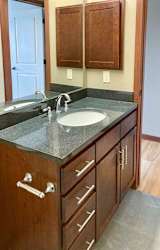 A bathroom with a granite vanity sink, a large mirror, and a medicine cabinet.
