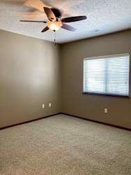 A bedroom with a ceiling fan and a window with blinds.
