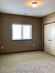A bedroom with a window and two side-by-side closets.