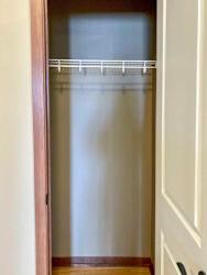 A hallway coat closet with a shelf.