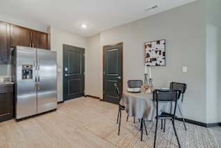 A kitchen with a table and chairs set up in front of it, next to the front entryway