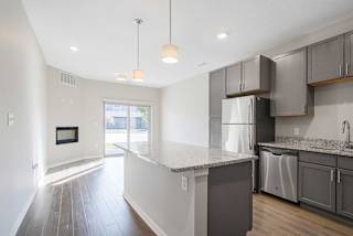 a open-concept kitchen with stainless steel appliances and granite counter tops next to a living room