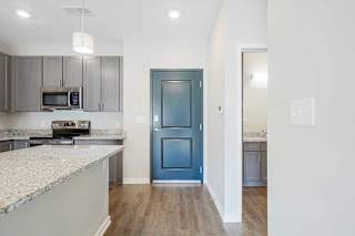 an open-concept kitchen with gray cabinets and stainless steel appliances next to a front door
