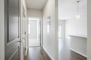 a hallway with a door open to a bedroom next to a kitchen and living room